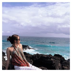 Woman looking at sea against sky