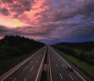 Road amidst trees against sky during sunset