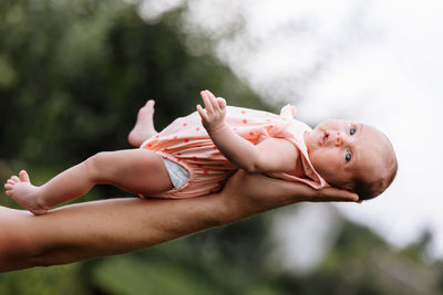 Cropped hand of mother holding baby outdoors