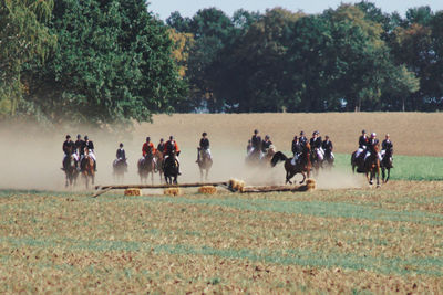 Group of people riding horses on a field at traditional fuchsjagd 
