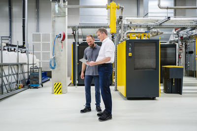 Employee and businessman with digital tablet talking in factory