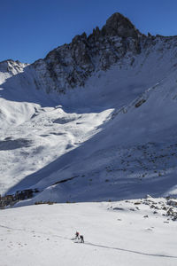 Two people backcountry ski amid jagged peaks in colorado.