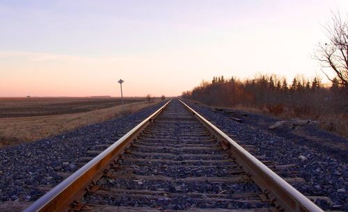 Railroad tracks against sky during sunset