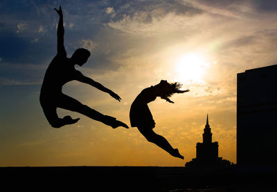 Low angle view of silhouette man jumping against sky during sunset