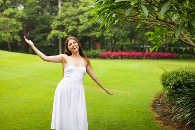 Full length of a smiling young woman standing on green grass