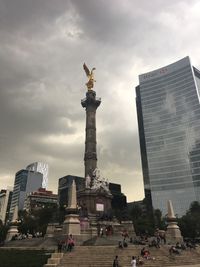 Statue in city against cloudy sky