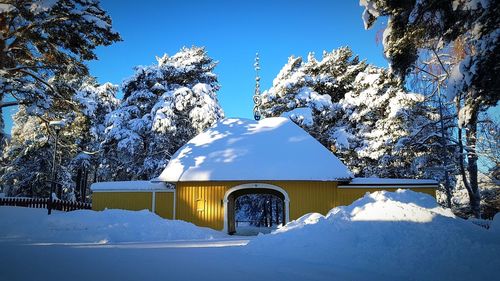 Snow covered houses and trees against sky