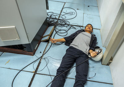 Shocked man holding cables while lying on floor by fuse box