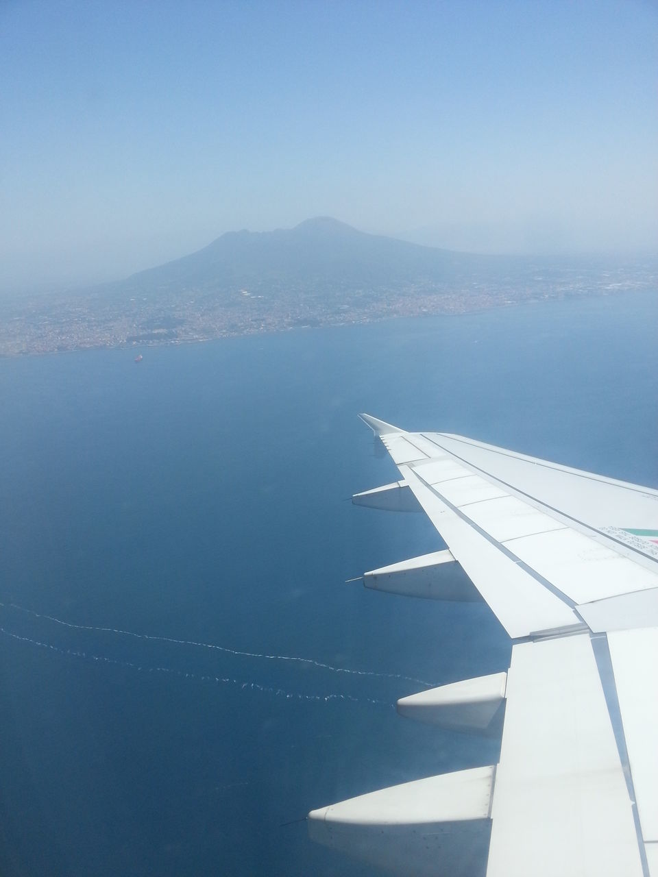 flying, airplane, aircraft wing, air vehicle, transportation, aerial view, sea, part of, clear sky, mode of transport, blue, cropped, water, scenics, mid-air, travel, sky, copy space, nature, beauty in nature