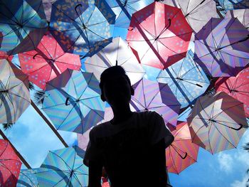 Low angle view of man under umbrellas against sky