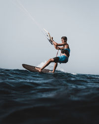 Side view of man in sea against clear sky