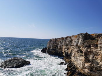 Rocks on shore by sea against sky