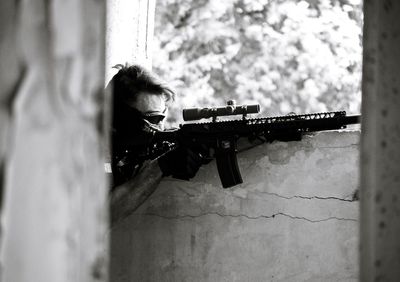 Side view of military man aiming from abandoned building