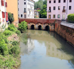 Arch bridge over river amidst buildings in city