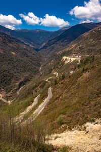 Mountain valley with curvy road and bright blue sky at sunny day from top