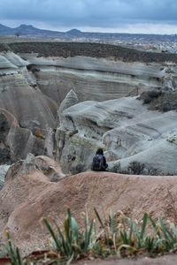 Rear view of woman sitting on rock formation at cappadocia