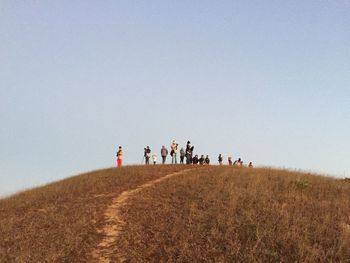 People walking on field against clear sky