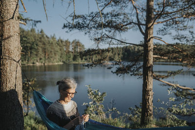 Senior woman resting in hammock at lakeshore