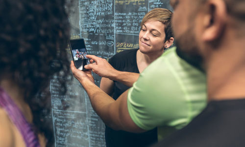 Young man photographing woman using smart phone