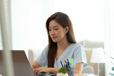 Young woman using phone while sitting on table