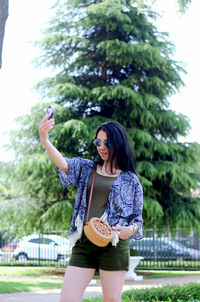 Young woman standing against trees