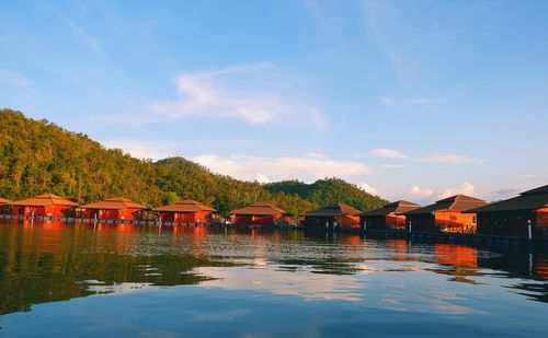 Houses by lake and buildings against sky