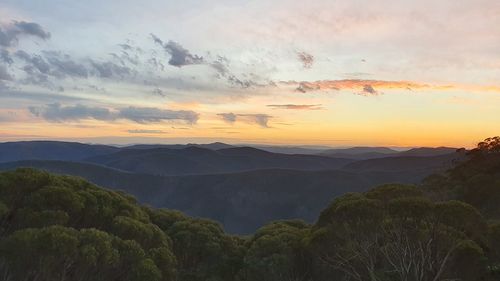 Scenic view of mountains against dramatic sky during sunset