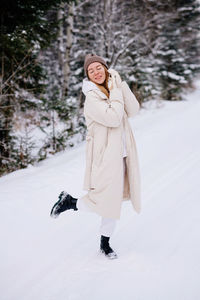 Caucasian woman in white warm jacket walking in winter forest. winter clothing. full body portrait  
