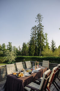 Food and drinks arranged on table with chairs in back yard