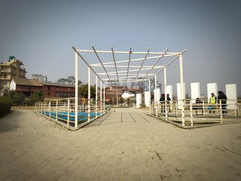 Rear view of people walking on footpath against buildings