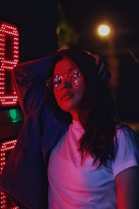 Portrait of young woman standing outdoors at night