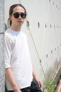 Portrait of young man wearing sunglasses while standing against urban architecture 