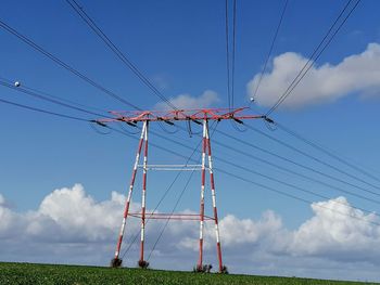 Low angle view of electricity pylon on field against sky