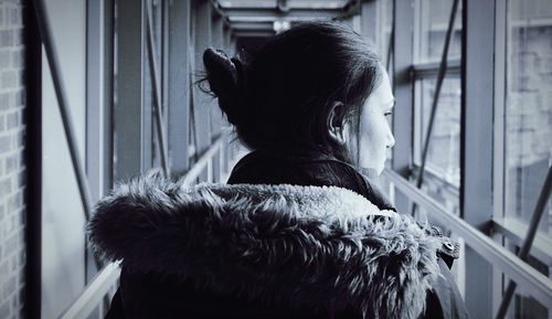 Rear view of woman looking through window at home