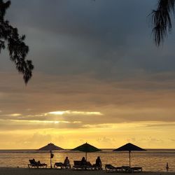 Silhouette people on beach against sky during sunset