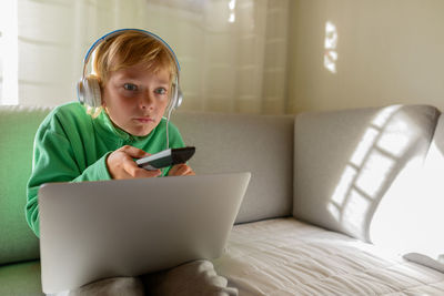 Boy wearing headphones watching tv at home