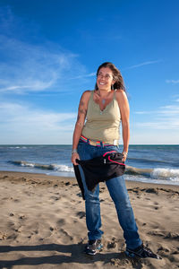 Full length portrait of smiling young woman on beach