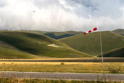 Scenic view of landscape and wind sleeve against sky