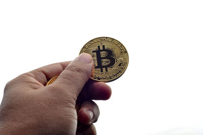 Close-up of hand holding coins against white background