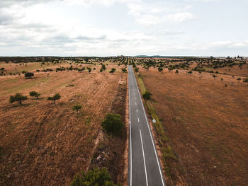 Panoramic view of road amidst field against sky