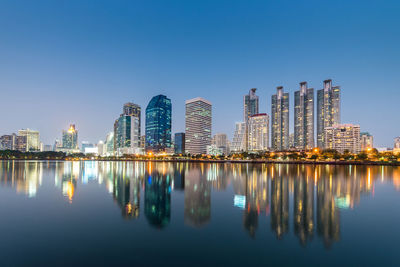 Reflection of buildings in city against clear sky