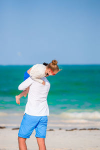 Rear view of woman on beach against sky