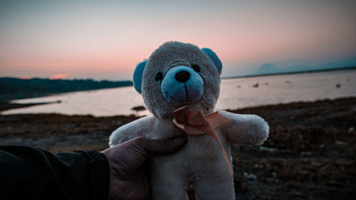 Close-up of hand holding sunglasses against sky at sunset