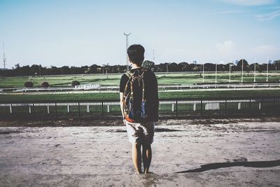Rear view of man standing against horseracing track