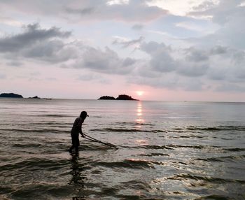 Silhouette man on beach against sky during sunset