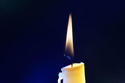 Close-up of illuminated candle against black background