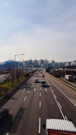 Vehicles on road against sky in city