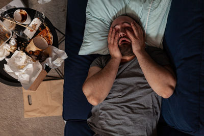 Depressed frustrated man in despair laying on couch, feeling irritated about solitude and loneliness