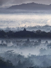 Scenic view of fog covered mountains against sky
