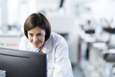 Smiling female engineer using computer at factory